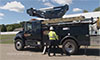 Photo of a man standing in front of a hybrid utility truck