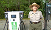 Photo of a female national park ranger next to a DC charger.